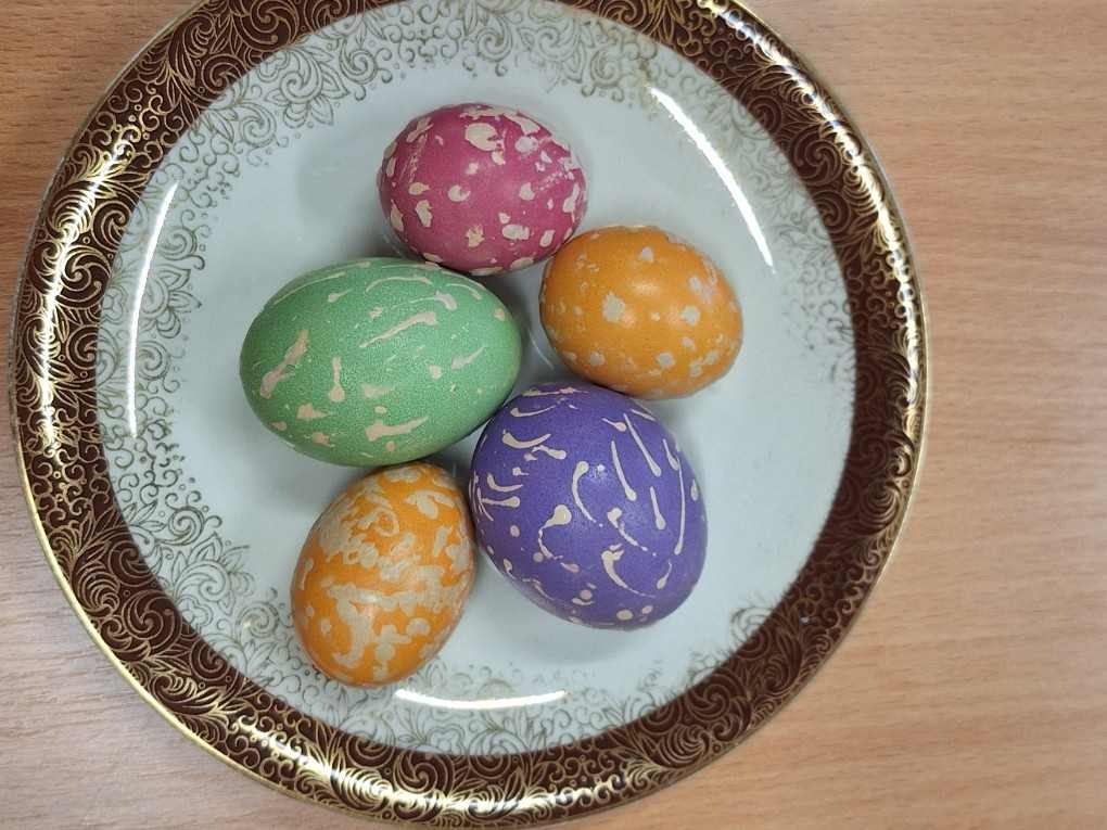 Jajka w kolorze: żółtym, zielonym, niebieskiem i różowym leżace na talerzu