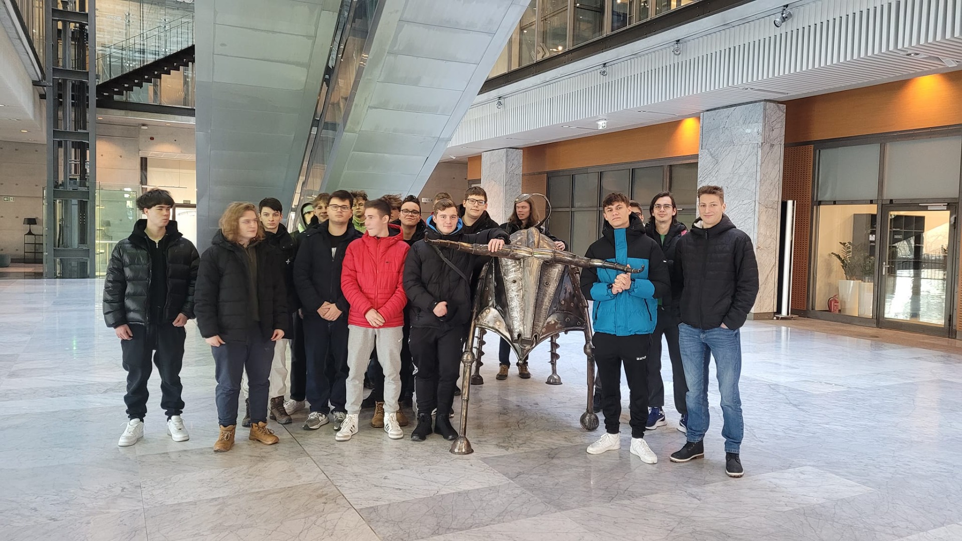 Grupa uczniów w budynku giełdy z inną rzeźbą byka. 