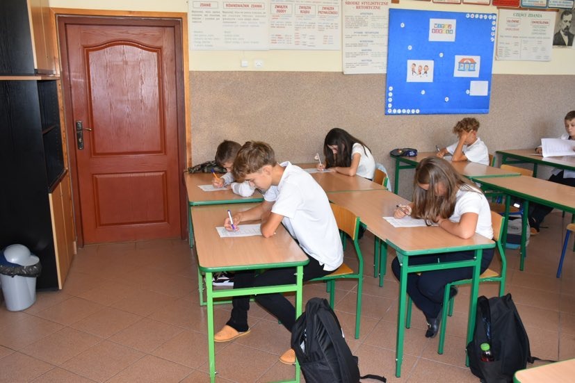 Uczniowie siedzą w ławkach i piszą test konkursowy