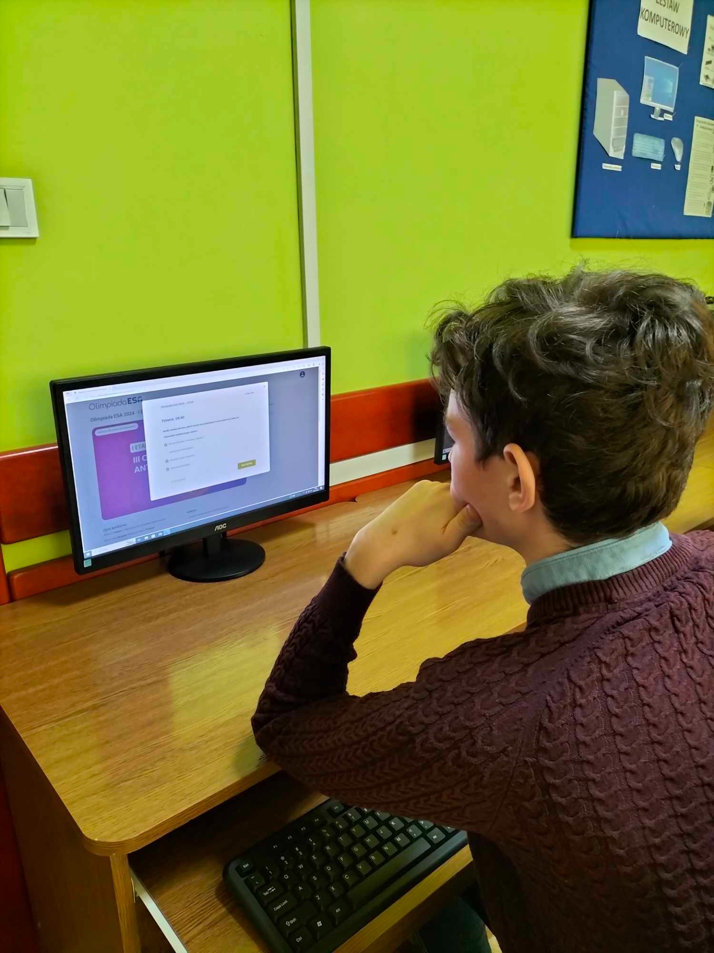 Uczniowie w pracowni komputerowej rozwiązują test konkursowy online.