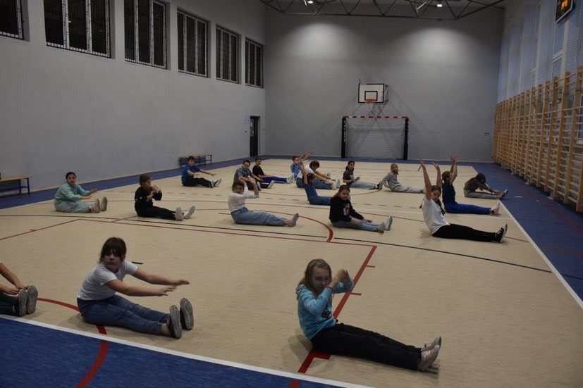 Uczniowie ćwiczą układy taneczne na sali gimnastycznej