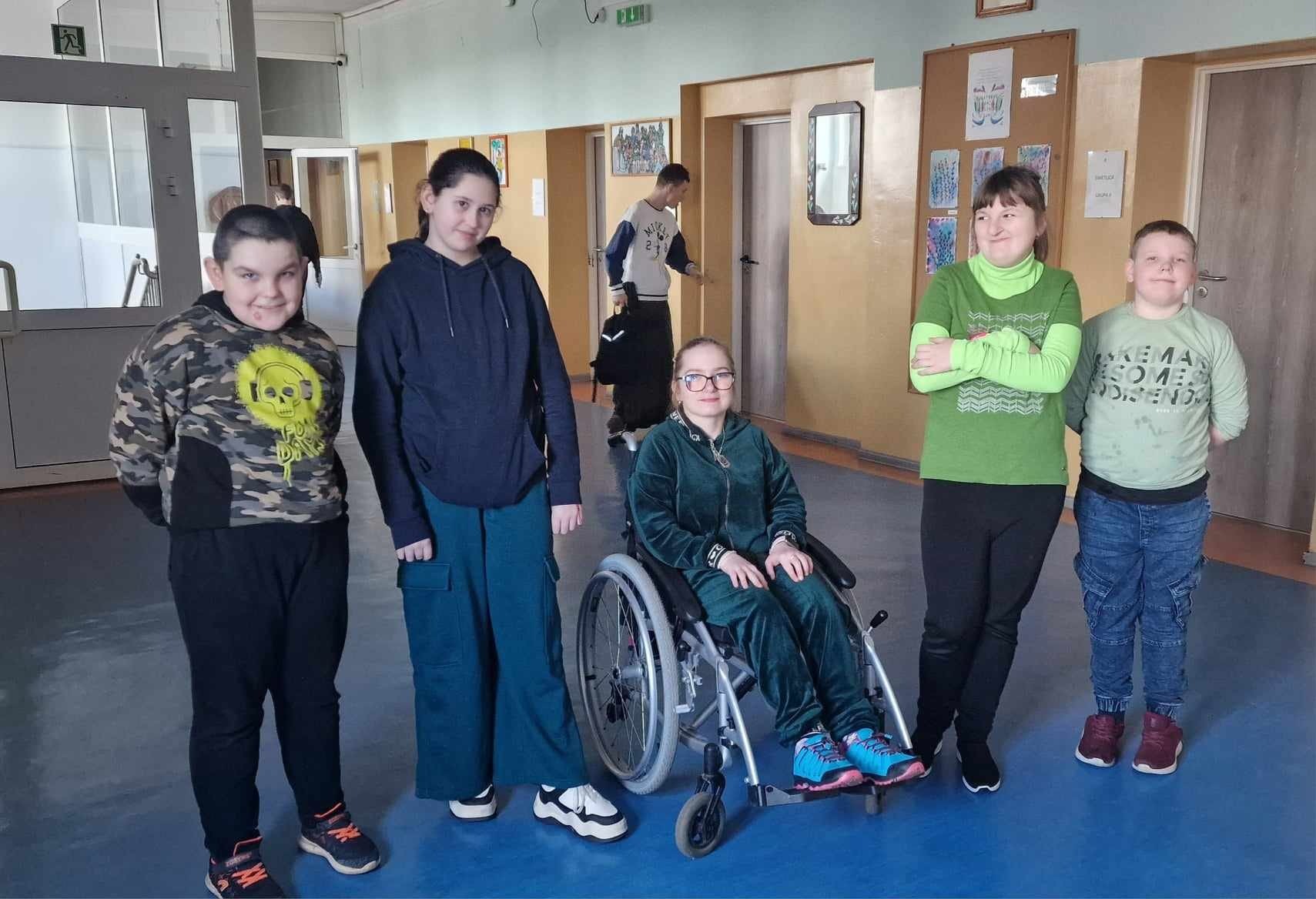 5 uczniów, w tym 1 na wózku inwalidzkim pozuje do zdjęcia - mają zielone dodatki w ubiorze
