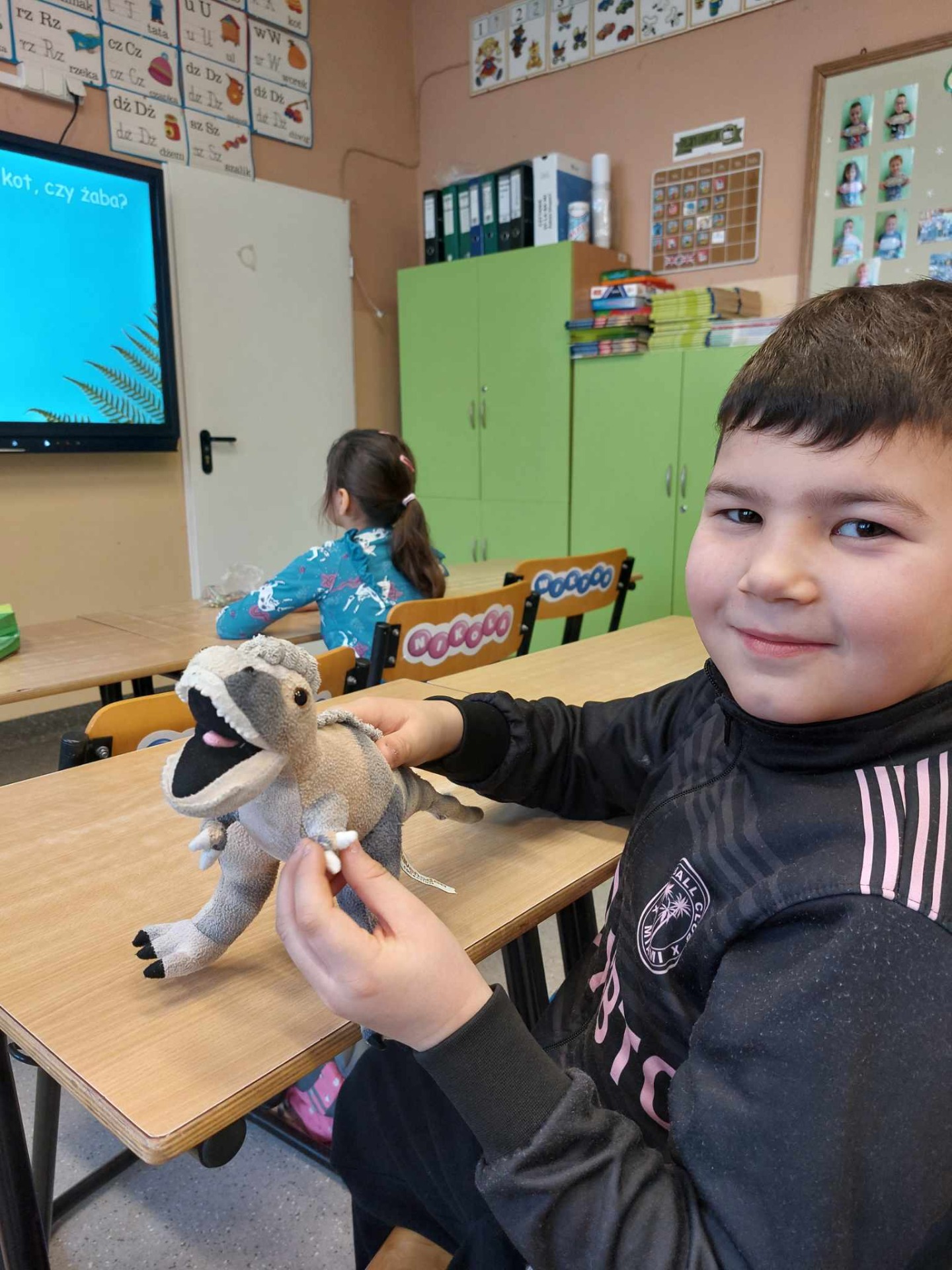 Uczeń pokazuje maskotkę dinozaura