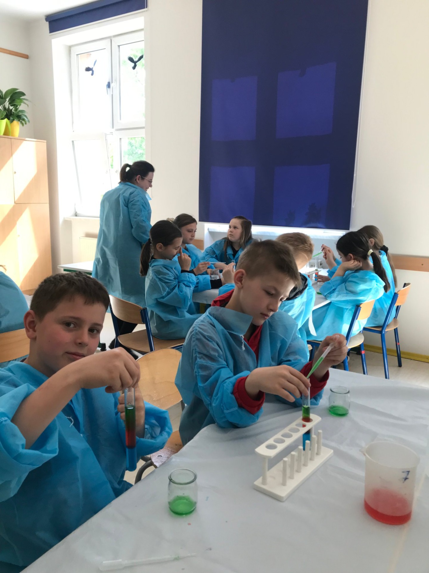 Grupa dzieci przy stolikach podczas eksperymentów Unikids