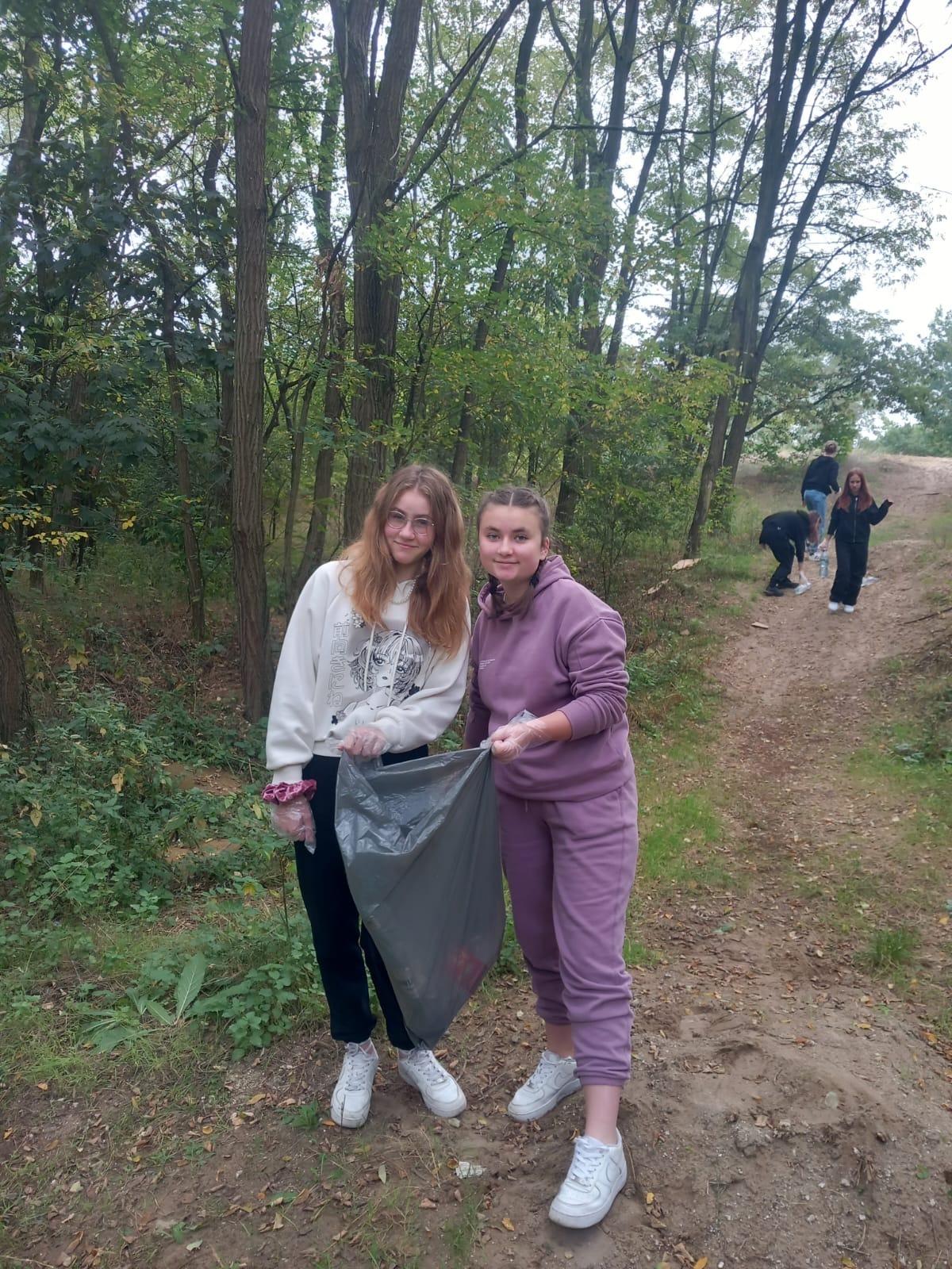 dziewczęta w lesie sprzątają śmieci