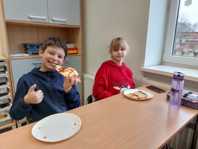 Uczniowie jedzący pizzę.